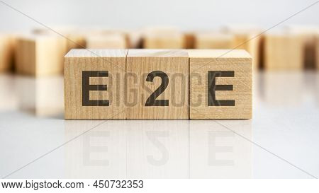 E2e Word Written On Wood Block, Business Concept. E2e - Short For Exchange To Exchange
