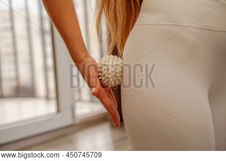 Athletic Slim Caucasian Woman Doing Thigh Self-massage With A Massage Ball Indoors. Self-isolating M