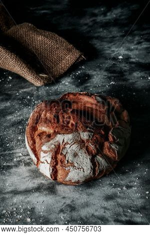 a round kamut wheat bread loaf on a mottled dark gray fabric surface