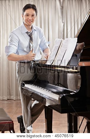Un compositeur de musique jeunes debout près de piano à queue