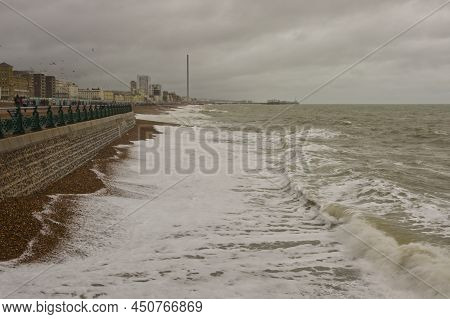 Grey And Stormy Day On Seafront At Brighton In East Sussex, England. With Unrecognisable People On P