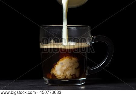 Cream Is Poured Into Coffee On A Black Background. Tonic Coffee Drink. Coffee With Milk