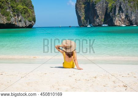 Woman Tourist In Yellow Swimsuit And Hat, Happy Traveller Sunbathing At Maya Bay Beach On Phi Phi Is