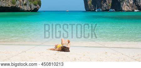Woman Tourist In Yellow Swimsuit And Hat, Happy Traveller Sunbathing At Maya Bay Beach On Phi Phi Is