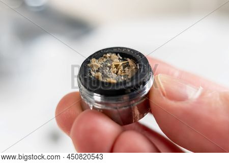 A Clogged Dirty Faucet Aerator With Calcium Plaque In The Hand Of A Plumber. Tap Filter Above The Ba