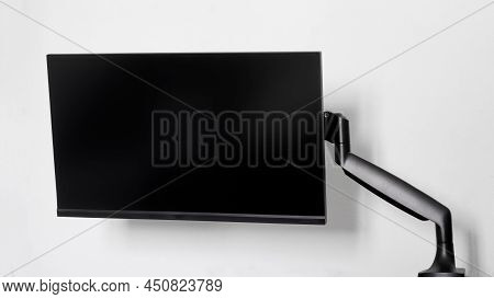 A Modern Frameless Thin Computer Monitor Or Tv Is Mounted On A Metal Swivel Desktop Bracket With A G
