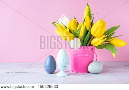 Easter Holiday Decorations: Wooden Eggs And Bouquet Of Yellow Tulips In Bucket On Pink Background. C