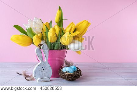Easter Holiday Decorations: Wooden Funny Bunnie, Eggs In Bird Nest And Bouquet Of Yellow Tulips In B