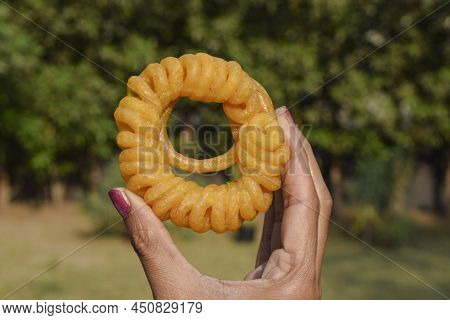 Female Holding Imarti Sweet. Jalebi Sweet In Hand Outdoors Background.