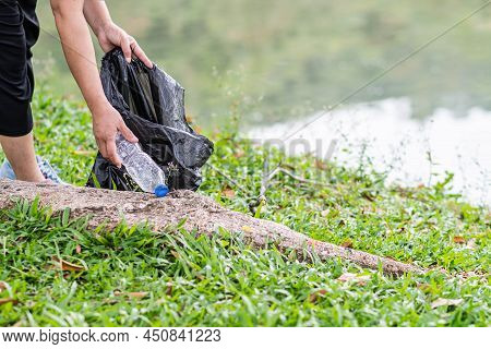 A Woman Cleans Up By Picking Up Plastic Bottles At A Natural Water Reservoir. Concept Of Protecting 