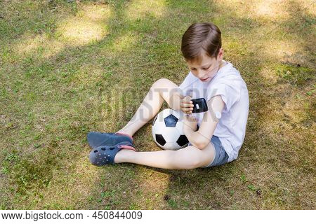 Boy Sitting On The Grass In The Open Air With Ball And Measuring Sugar Levels