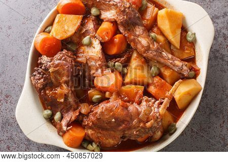Rabbit Stewed In Red Wine With Vegetables And Garlic Close-up In A Saucepan On The Table. Horizontal