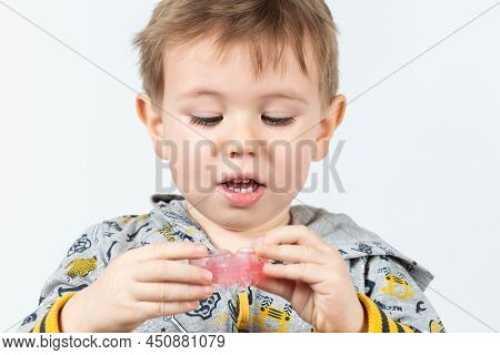 Cute Little Caucasian Boy With Blond Hair Is Holding A Pink Dental Myofunctional Trainer On White Th