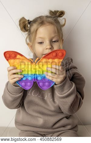 The Girl Holds A Popular Toy Pop It In The Shape Of A Butterfly And Looks At It. Sensory Game For Tr