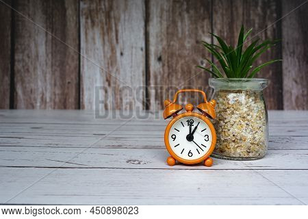 Orange Alarm Clock Isolated On Wooden Desk. The Clock Set At 1 O'clock. Deadline Concept.