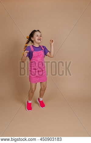 Delighted Thrilled Jumping Small Child With Yellow Kanekalon Pigtails Dancing Looking Up Smiling Wit
