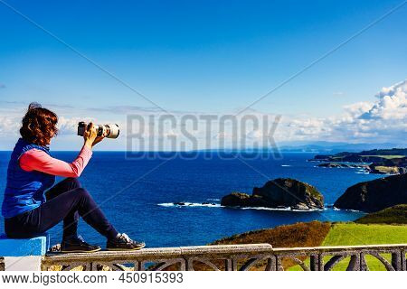 Woman With Camera Take Travel Photo From Seascape Of Atlantic Ocean And Asturias Coast At Cape Penas