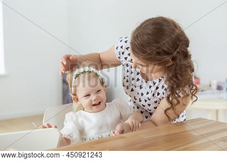 Mother Helps To Put On Cochlear Implant For Her Deaf Little Daughter. Hearing Aid And Deafness Conce