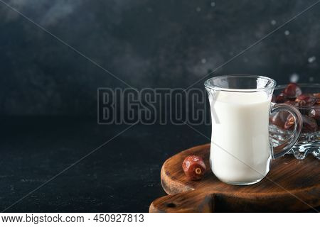 Ramadan Kareem Food And Drinks. Plate Of Dates, Glass Of Milk And Date Palm Branch On Black Backgrou