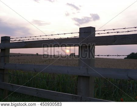 Sunset Background And Barbed Wire Fence Silhouette
