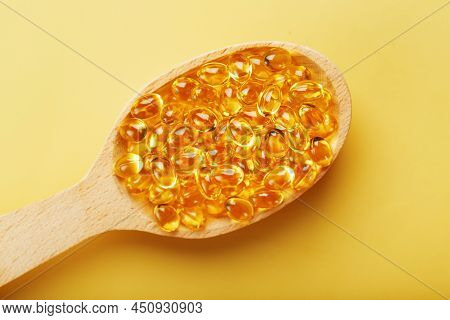 Vitamin D3 In A Wooden Spoon On A Bright Yellow Background