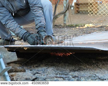 Worker Cutting Iron Sheet With Sparks In Front Of Workshop, Sawing And Recycling Old Metal, Cutting 
