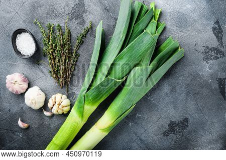 Leek Stalks On  With Herbs Ingredients For Coocing Braised Leeks, On Grey Textured Table Top View Wi