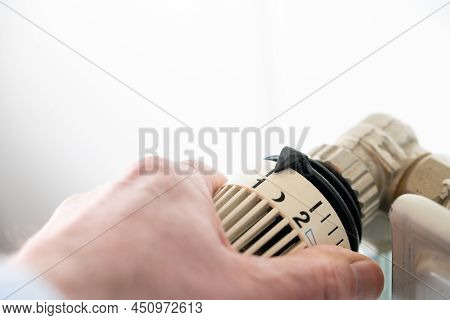 Close-up Of Hand Turning Thermostat Down. Turn Heating Off. Gas Price. Savings. High Quality Photo