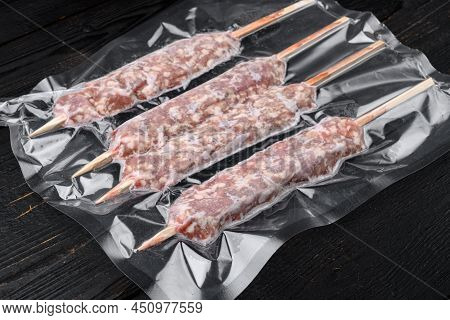 Raw Traditional Romanian Mititei In Vacuum Pack Set, On Black Wooden Table Background