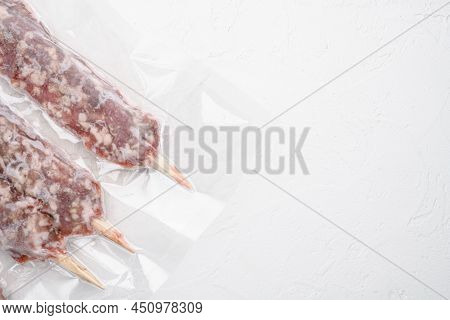 Raw Traditional Romanian Mititei In Vacuum Pack Set, On White Stone Table Background, With Copy Spac