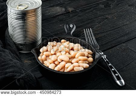 White Canned Beans Set, With Metal Can, In Cast Iron Frying Pan, On Black Wooden Table Background, W