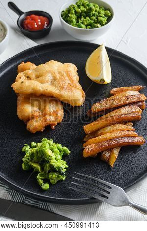 British Traditional Fish And Chips With Minty Mashed Peas Detail And A Slice Of Lemon. On Black Roun