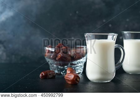 Ramadan Kareem Food And Drinks. Plate Of Dates, Glass Of Milk And Date Palm Branch On Black Backgrou