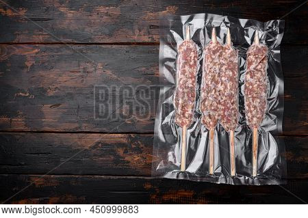 Raw Traditional Romanian Mititei In Vacuum Pack Set, On Old Dark  Wooden Table Background, Top View 