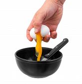 Hand Breaking Chicken Egg Into Black Bowl.