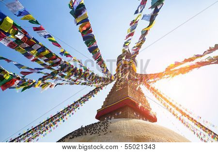 Prayer flags flying against the sun from the Boudhanath Stupa - symbol Kathmandu, Nepal.