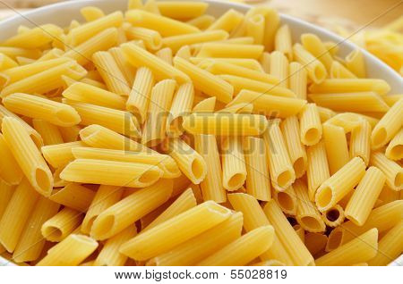 a plate with uncooked penne rigate on a table, ready to be boiled