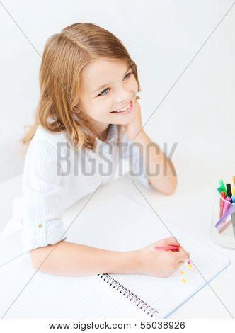 education, creation and school concept - smiling little student girl drawing and daydreaming at school