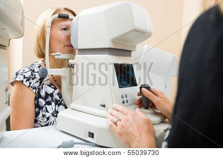Female optician examining patient's eye pressure with tonometer
