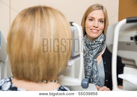 Young Optometrist measuring patients eye pressure with tonometer