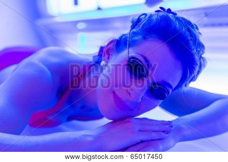 Woman in bikini tanning in wellness spa solarium