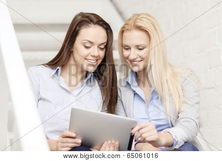 business, technology and startup concept - smiling creative team with tablet pc computer sitting on staircase