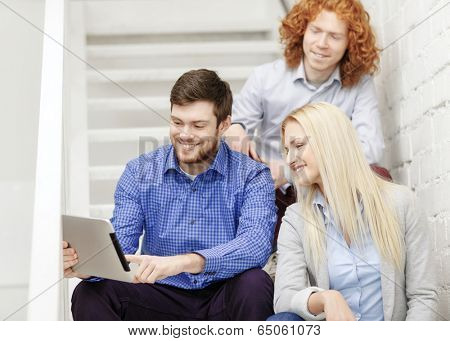 business, technology and startup concept - smiling creative team with tablet pc computer sitting on staircase