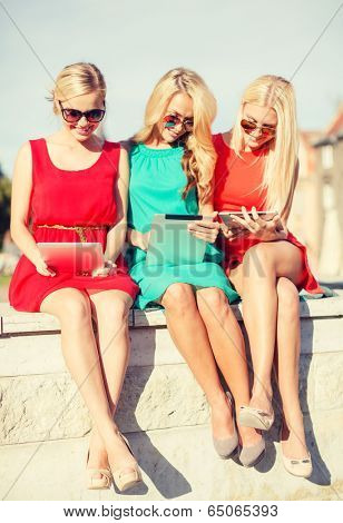 holidays and tourism concept - beautiful blonde girls toursits looking into tablet pcs in the city