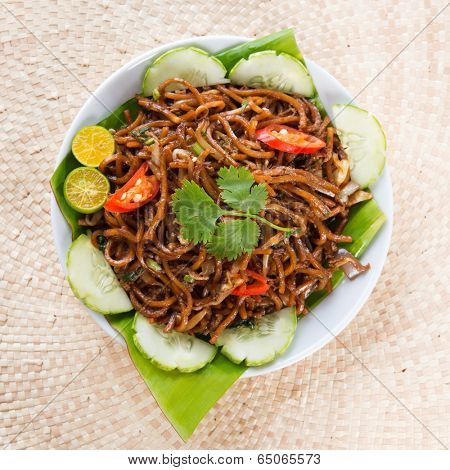 Asian food spicy fried noodles, ready to serve on dining table.