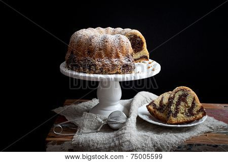 Marble bundt cake on wooden table, black background
