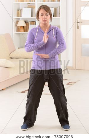Beautiful woman doing qi gong tai chi exercise at home