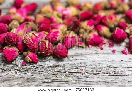 Dry tea rose buds on rustic wooden table