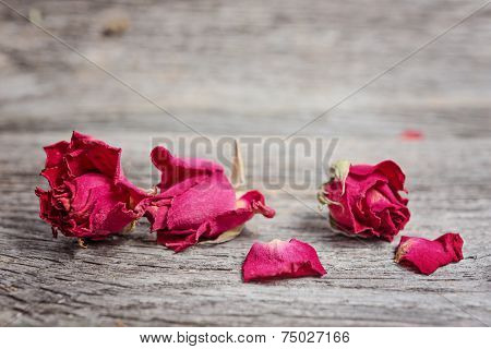 Dry tea rose buds on rustic wooden table