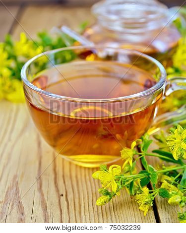 Tea from tutsan in glass cup and teapot on board